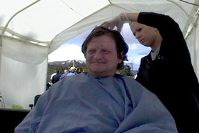 Chuck gets a hair cut from young lady volunteer